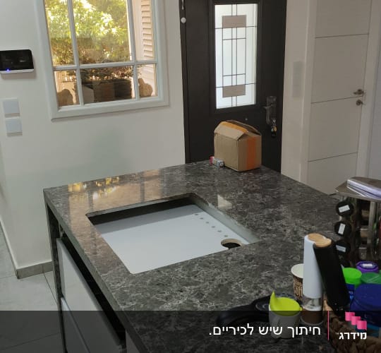 משטח שיש כהה במטבח מודרני עם כיור מובנה